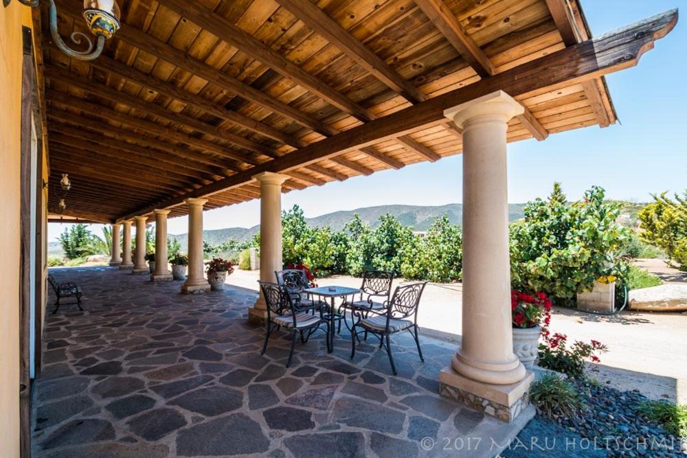 a patio with a table and chairs under a wooden roof at Quinta Estrella in Valle de Guadalupe