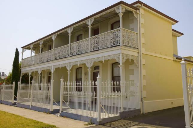 a yellow building with a white fence in front of it at King Street Apartments in Warrnambool