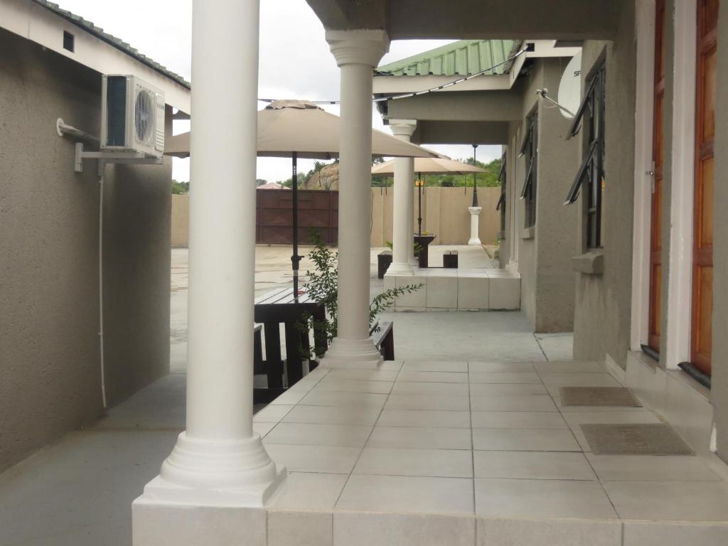 an outside view of a building with columns and an umbrella at BTV Guesthouse in Hazyview