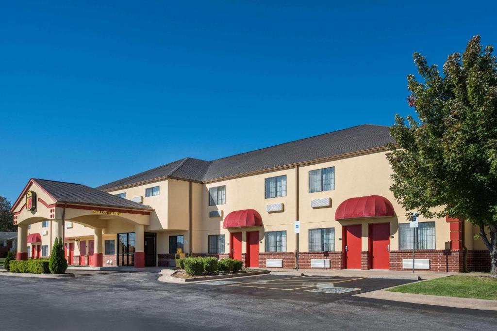 un hotel con toldos rojos en un edificio en Super 8 by Wyndham Claremore OK, en Claremore