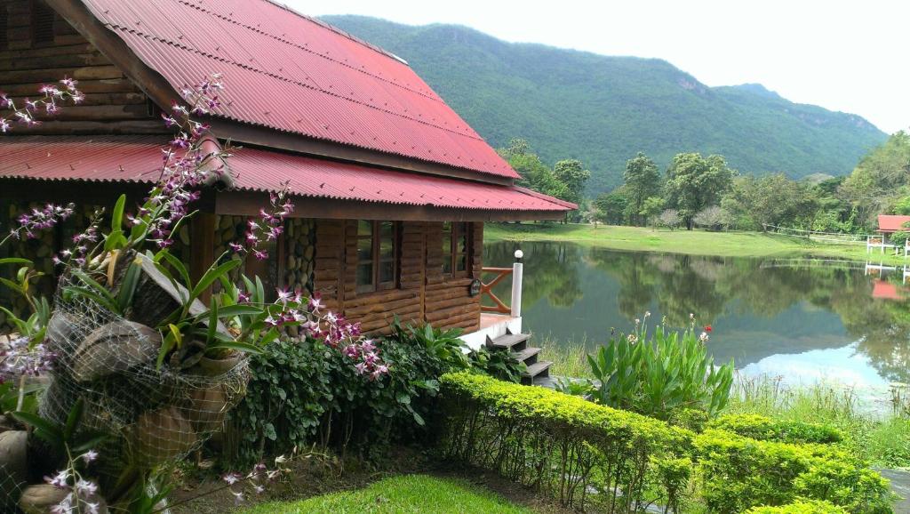 a house with a red roof next to a lake at River Kwai Park & Resort in Chongsadao