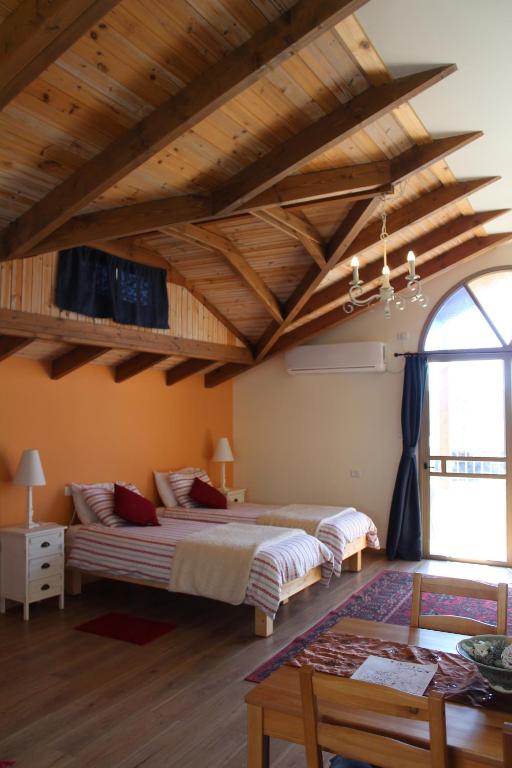 two beds in a large room with wooden ceilings at Off The Square in Safed