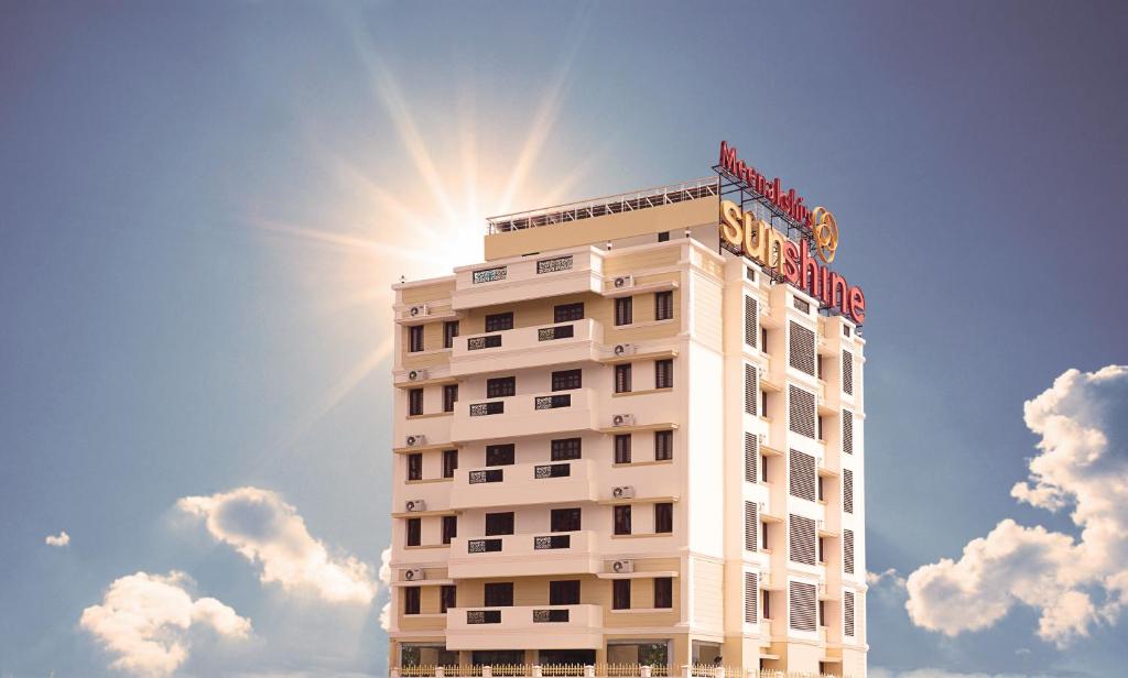 a white hotel building with the sun in the sky at Meenakshi's Sunshine Hotel in Madurai