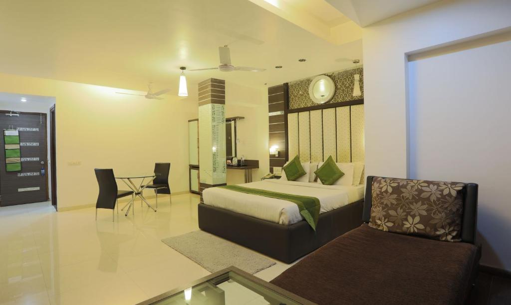 a bedroom with a bed and a couch and a table at Hotel Apple Inn Vapi in Vapi