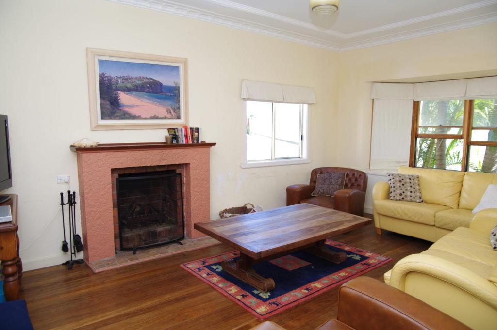 a living room with a table and a fireplace at Berry, 16 East Street in Crescent Head