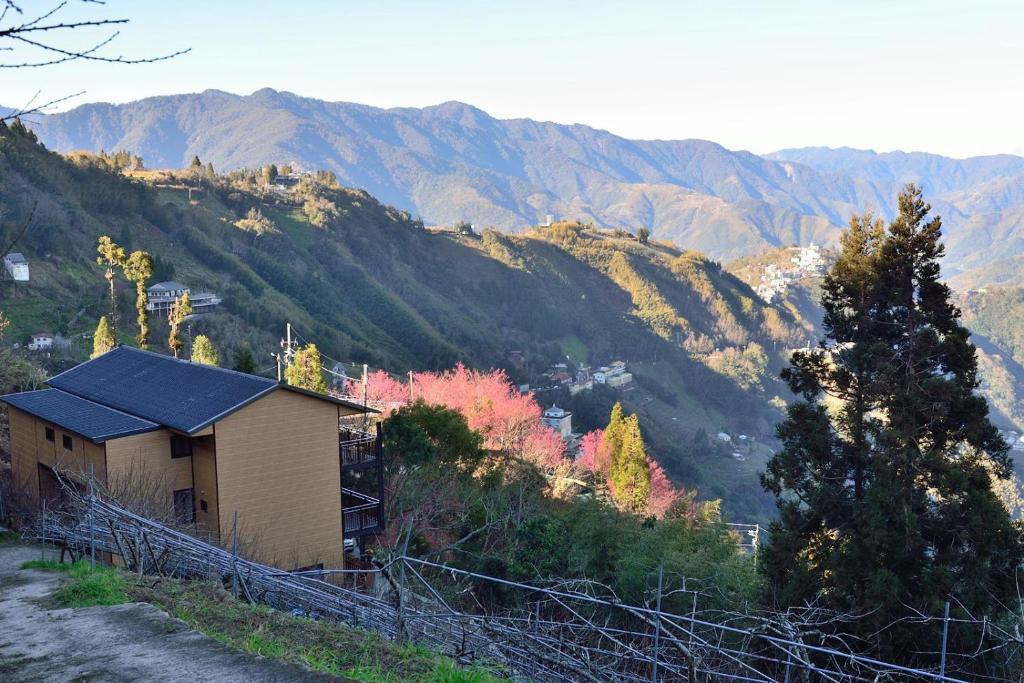 una casa en una colina con montañas en el fondo en The fairy land - Lala Mountain, en Fuxing