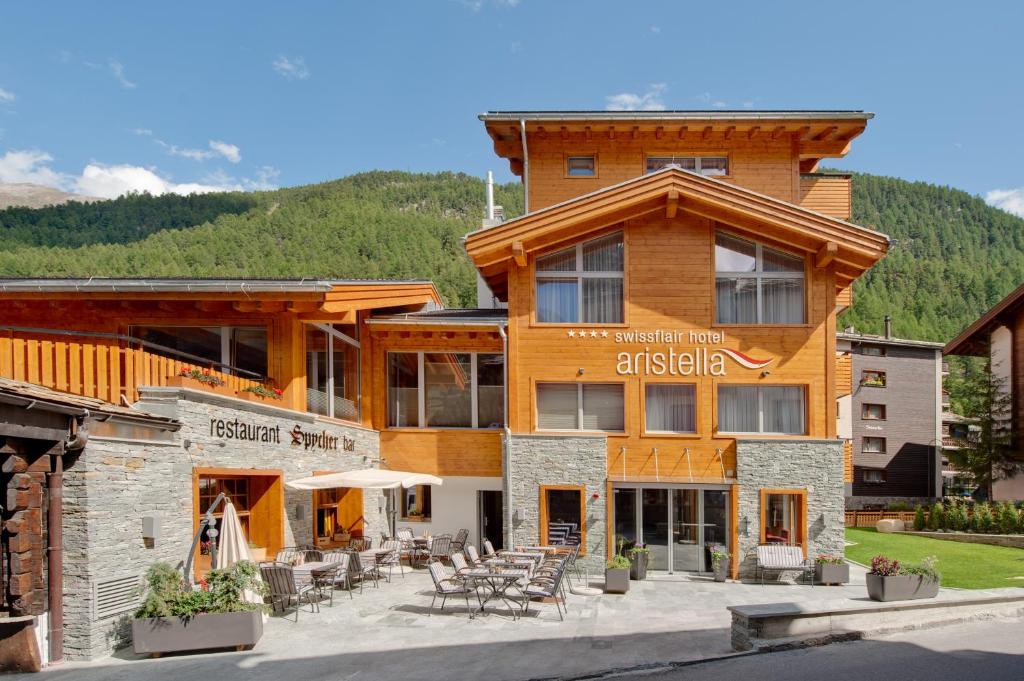 un bâtiment avec des tables et des chaises devant lui dans l'établissement Hotel Aristella Swissflair, à Zermatt