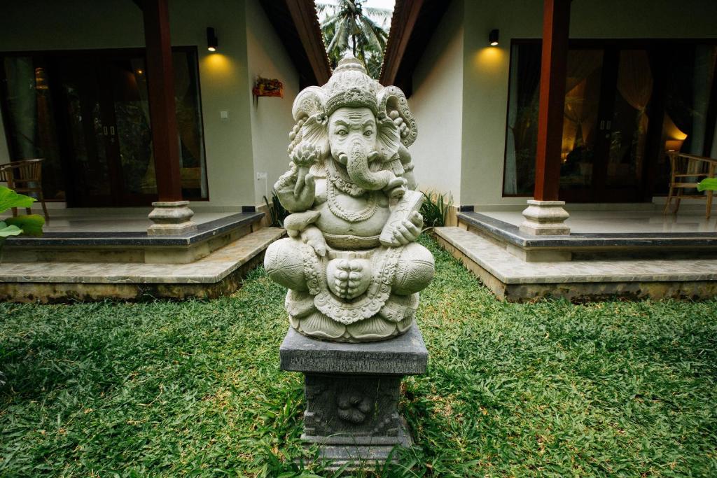 a statue in the grass in front of a building at Parthi Puri Ubud in Ubud