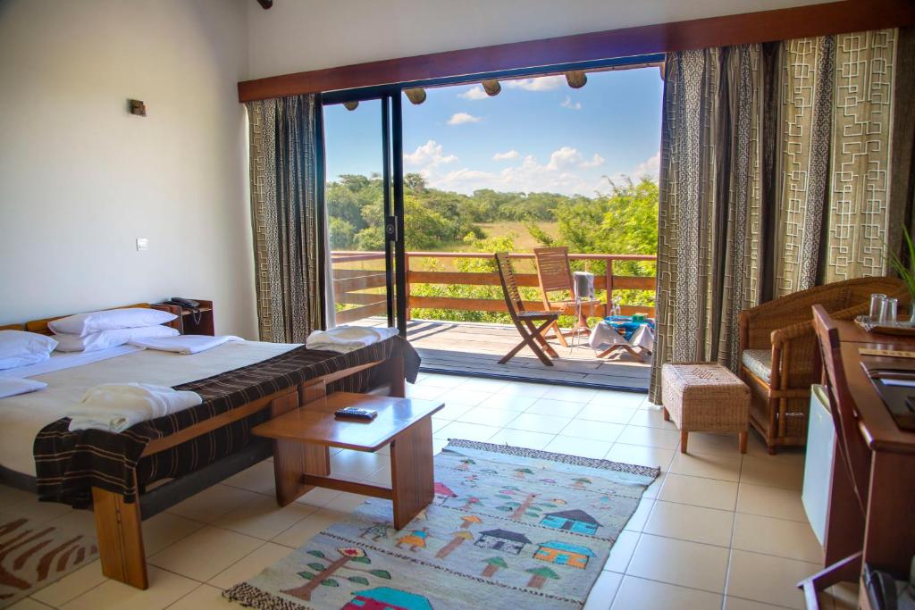 a bedroom with a bed and a balcony with a view at Chaminuka Lodge in Lusaka
