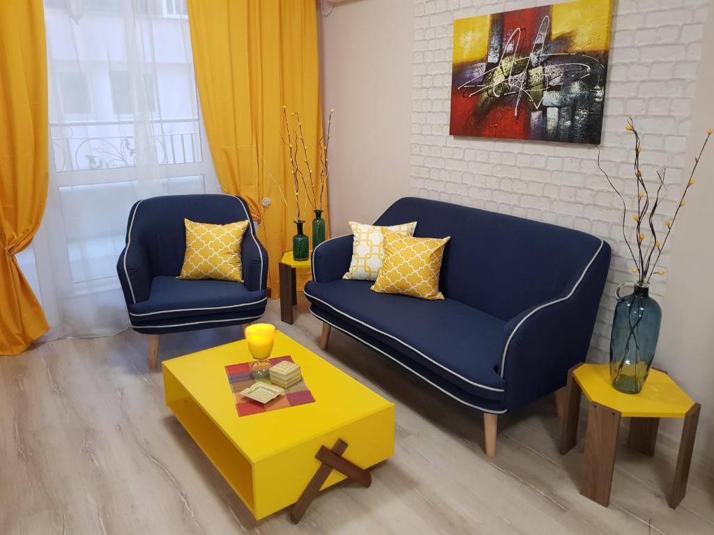 Best Guest Apartments في بلوفديف: غرفة معيشة مع كرسيين ازرق وطاولة صفراء