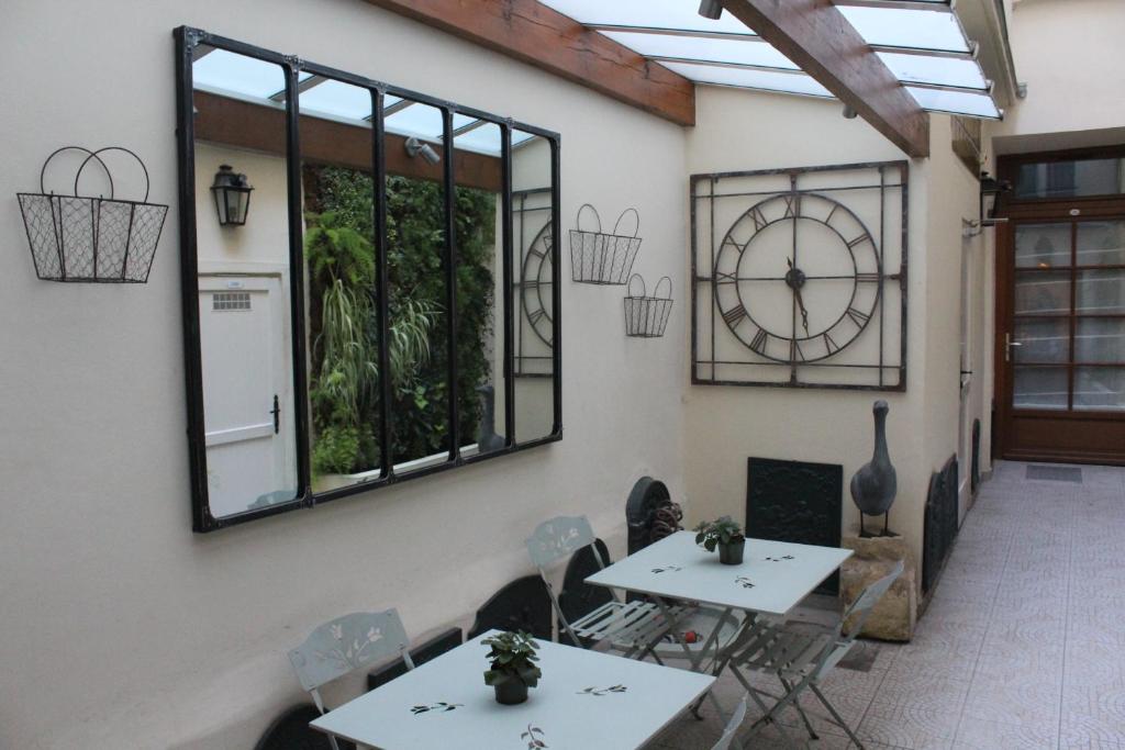 ein Zimmer mit zwei Tischen und einer Uhr an der Wand in der Unterkunft Hotel du Dragon in Paris