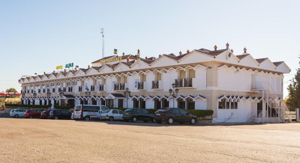 a large white building with cars parked in front of it at Hotel Alfar in Montilla