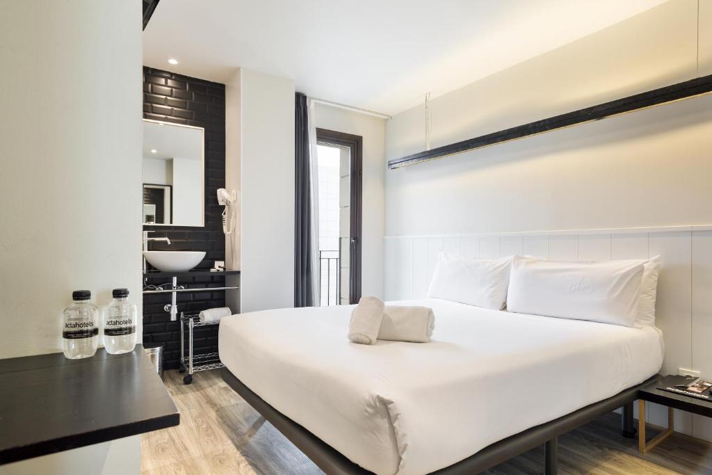 a bedroom with a large white bed and a bathroom at Acta BCN 40 in Barcelona