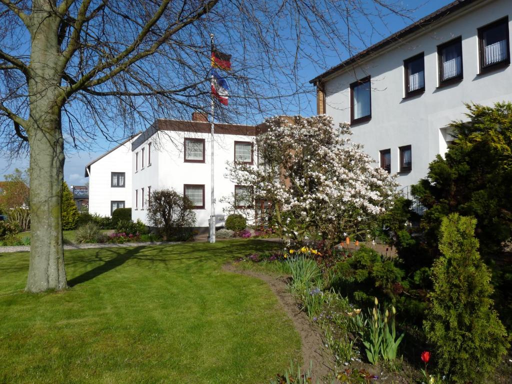 Biały dom z drzewem i ogródkiem w obiekcie Pension Haus Baltic w mieście Dahme
