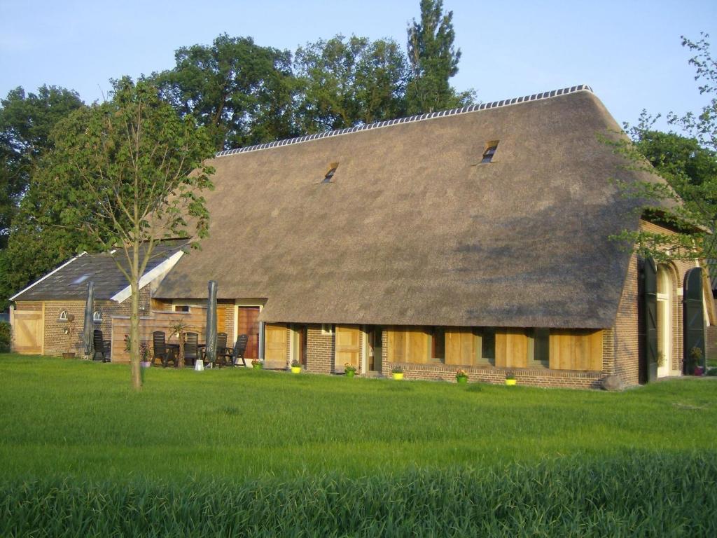 een groot bakstenen huis met een gambrel dak bij Staying in a thatched barn with bedroom and box bed beautiful view Achterhoek in Geesteren
