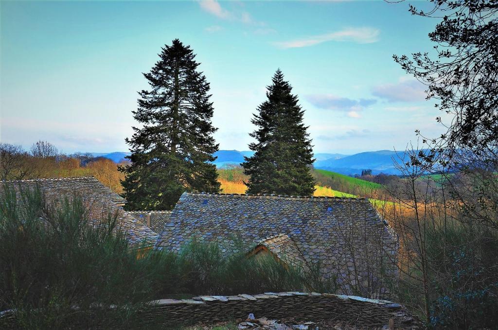 un antiguo edificio de piedra con árboles en el fondo en Domaine des Marequiers chambre Silène, en Saint-Germain-du-Teil