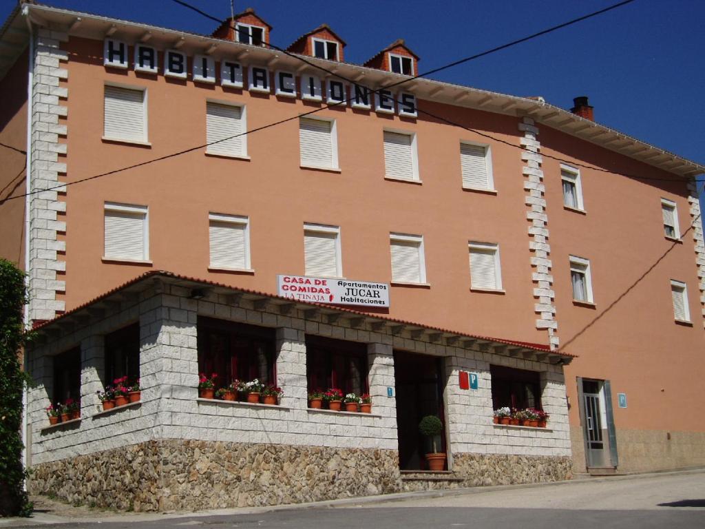 a large orange building with flowers in the windows at Apartamentos Jucar - Hotel Rural in Tragacete