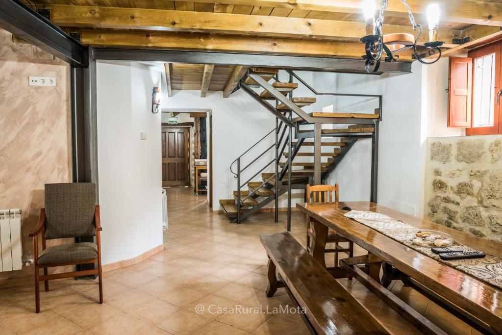 een eetkamer met een houten tafel en een trap bij Casa Rural "La Mota" in Astudillo