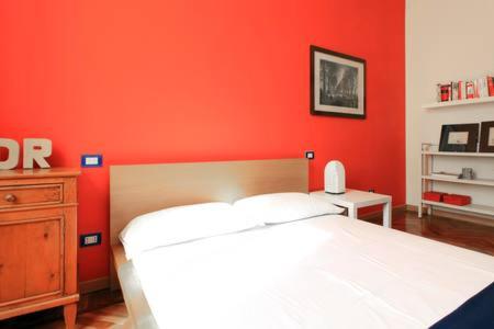 a red bedroom with a white bed and a wooden dresser at Appartamento centro storico corso magenta cadorna in Milan