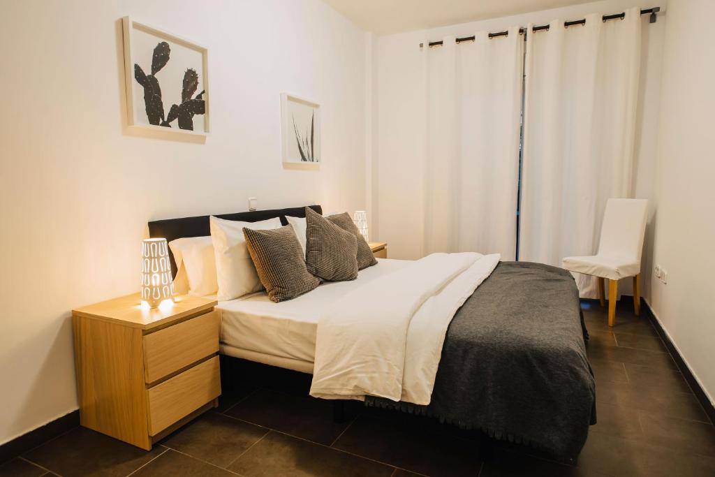 een slaapkamer met een groot bed en een stoel bij Cornisa Apartments in Patalavaca