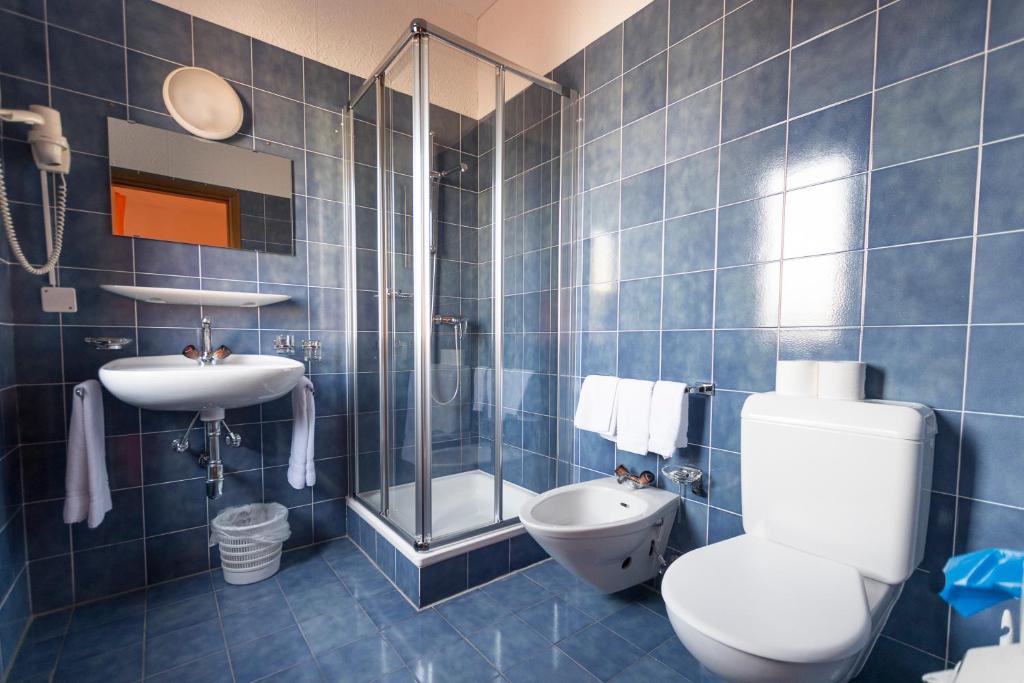 Baño de azulejos azules con aseo y lavamanos en Hotel Besso Lugano Center, en Lugano