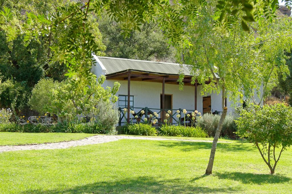 a white house with a table and chairs in a yard at Kranskloof Country Lodge in Oudtshoorn