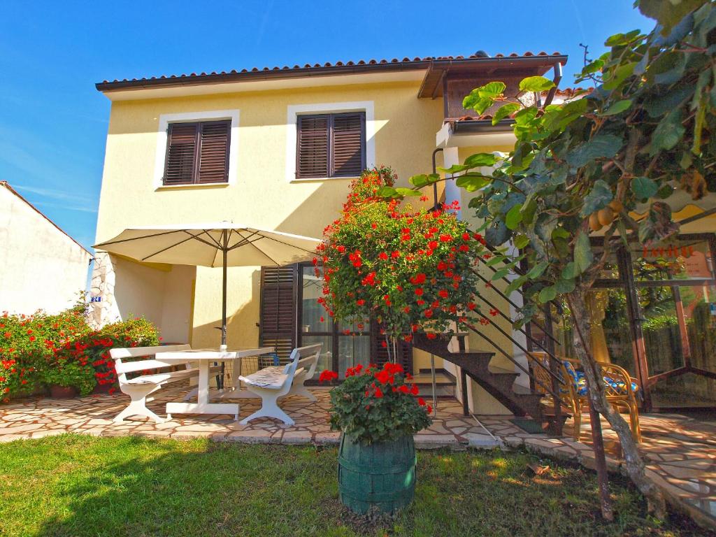 a house with a table and an umbrella in the yard at Apartments Slavko 1179 in Banjole