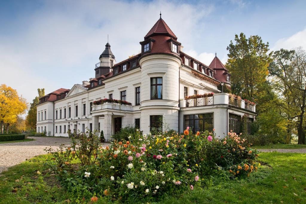 una gran casa blanca con flores delante en Pałac Wiejce, en Skwierzyna