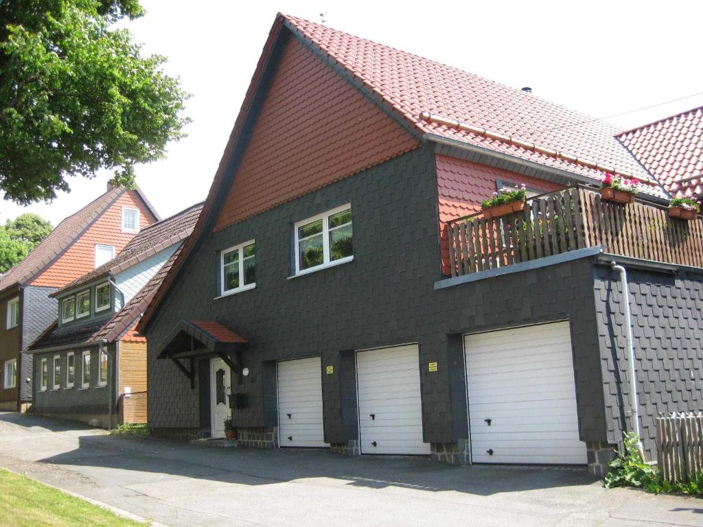 une maison avec deux portes de garage et un balcon dans l'établissement Ferienwohnung Becker, à Clausthal-Zellerfeld