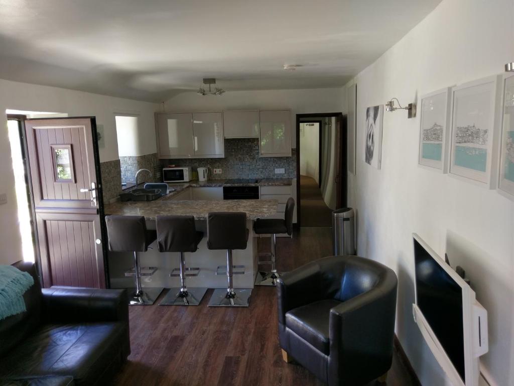 a living room with a couch and a kitchen at The Old Piggeries in Gulval