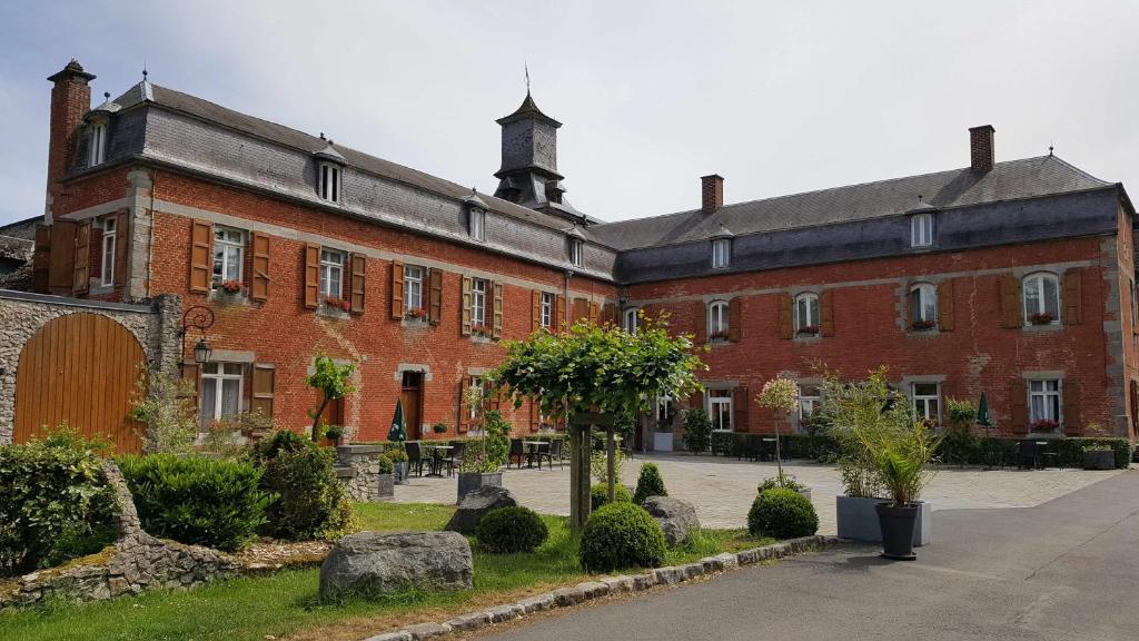 un grand bâtiment en briques rouges avec une cour dans l'établissement LOGIS - Château de la Motte - Hôtel & Restaurant, à Liessies