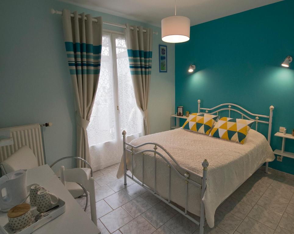 sypialnia z łóżkiem i niebieską ścianą w obiekcie Les Rendzines w mieście Nuisement-sur-Coole