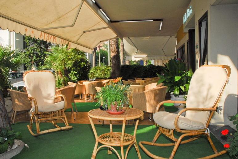 un patio con sillas, una mesa y una mesa con sillas en Hotel La Pineta, en Riccione