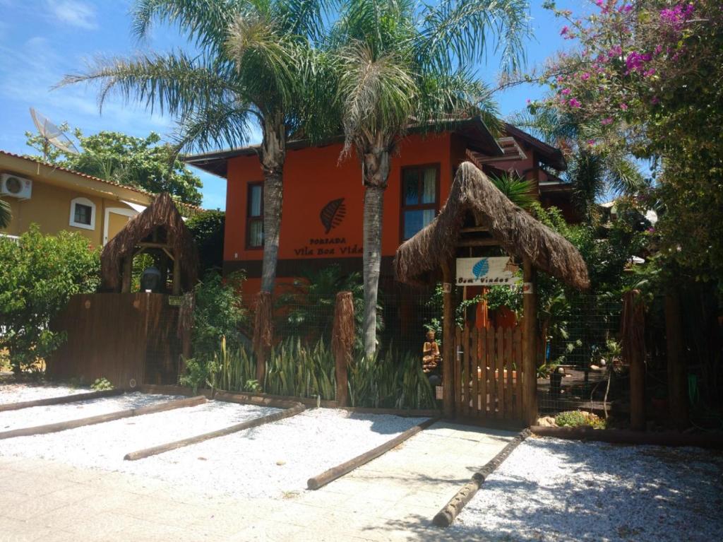 a house with a fence and a palm tree at Pousada Vila Boa Vida in Bombinhas