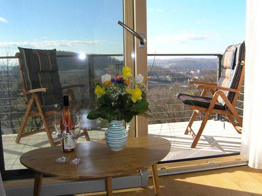 a table with a vase of flowers on a balcony at Apartmenthaus STYRIA in Bad Gleichenberg