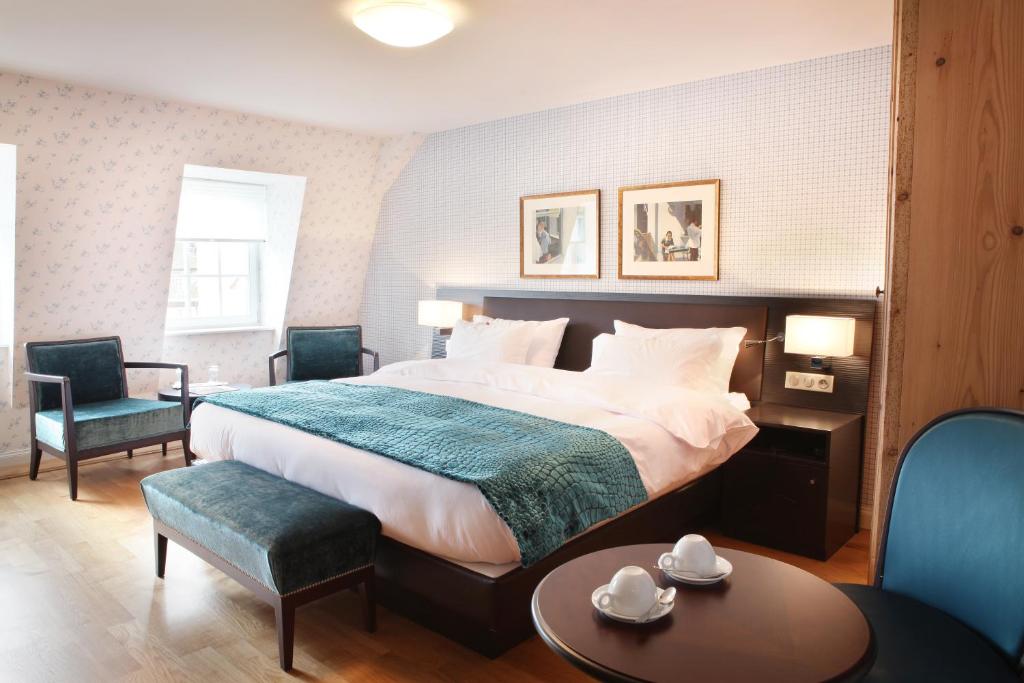 a bedroom with a large bed and a table and chairs at Hôtel Ettenheim in Strasbourg