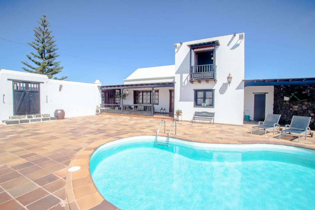 a villa with a swimming pool in front of a house at casa los veroles lanzarote in El Islote