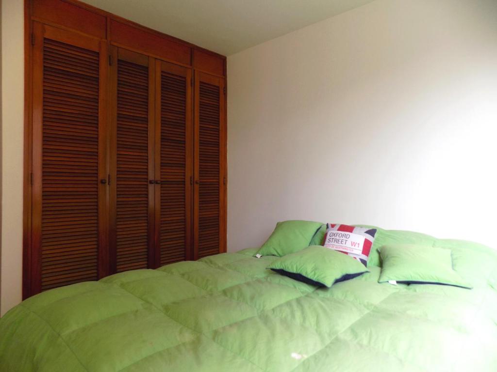 um quarto com uma cama com almofadas verdes em Room and private Bathroom at Chapinero Alto em Bogotá