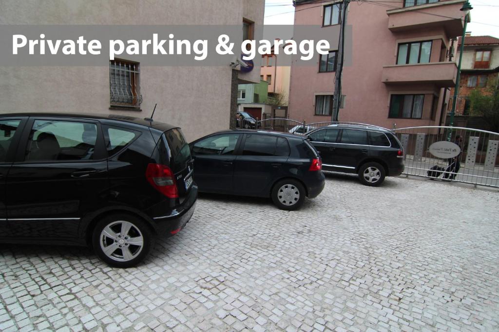 zwei Autos auf einem Parkplatz neben einem Gebäude geparkt in der Unterkunft Le Petit Prince in Sarajevo