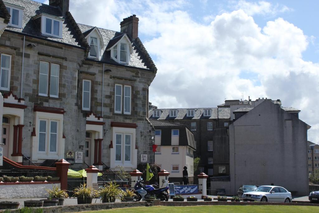 Un uomo in moto parcheggiato di fronte a una casa di Corran House Guest House a Oban