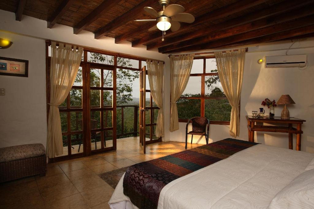 a bedroom with a bed and a table and windows at Samai Lodge Holistic Living in Olón