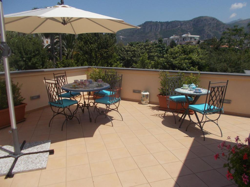 eine Terrasse mit einem Tisch, Stühlen und einem Sonnenschirm in der Unterkunft Domus Liberty in Sant'Agnello