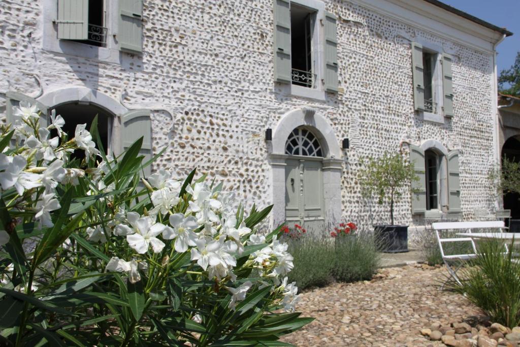 un bâtiment avec des fleurs blanches devant lui dans l'établissement Vintage Vert, à Lahitte-Toupière