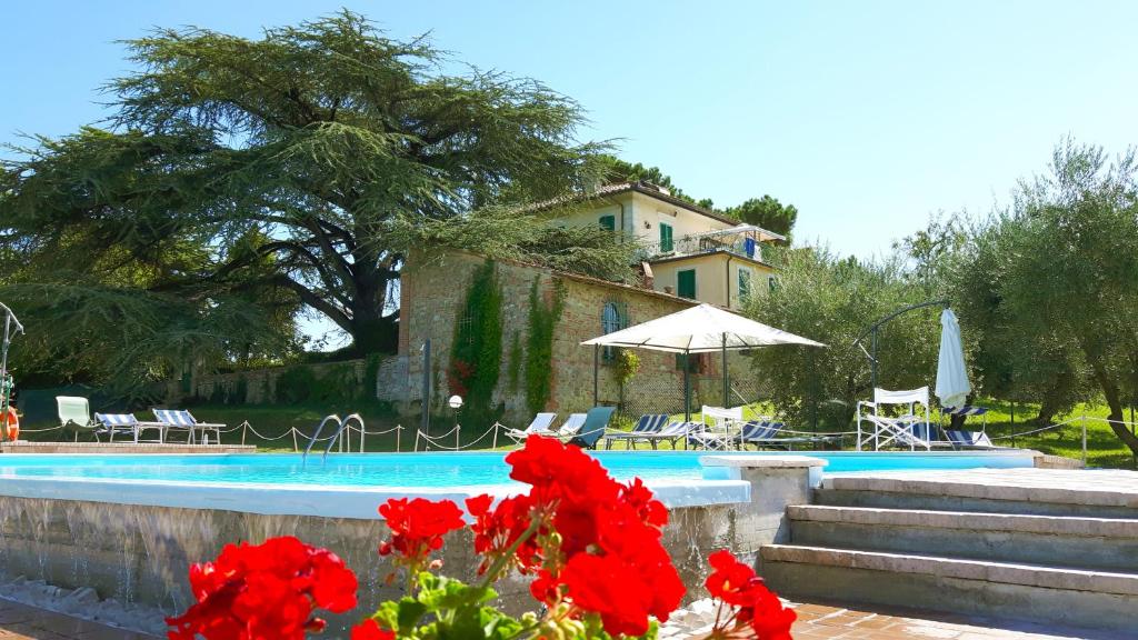 a swimming pool with red flowers in front of a house at Villa La Fontana in Castiglione del Lago