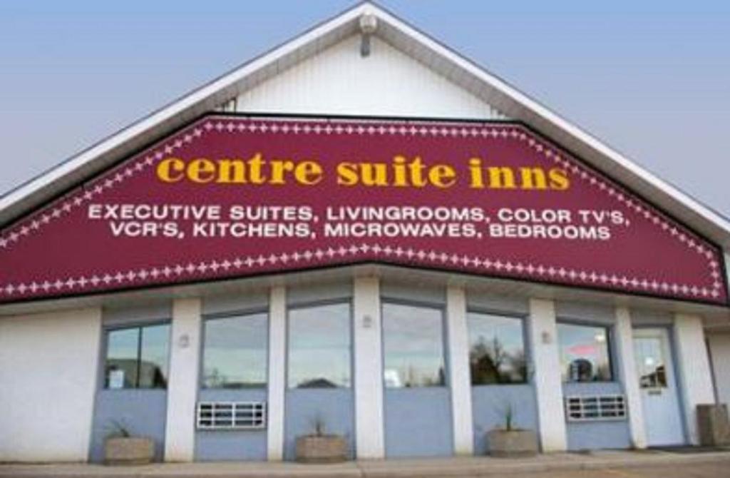 a building with a red and yellow sign on it at Centre Suite Inns Motel in Bonnyville