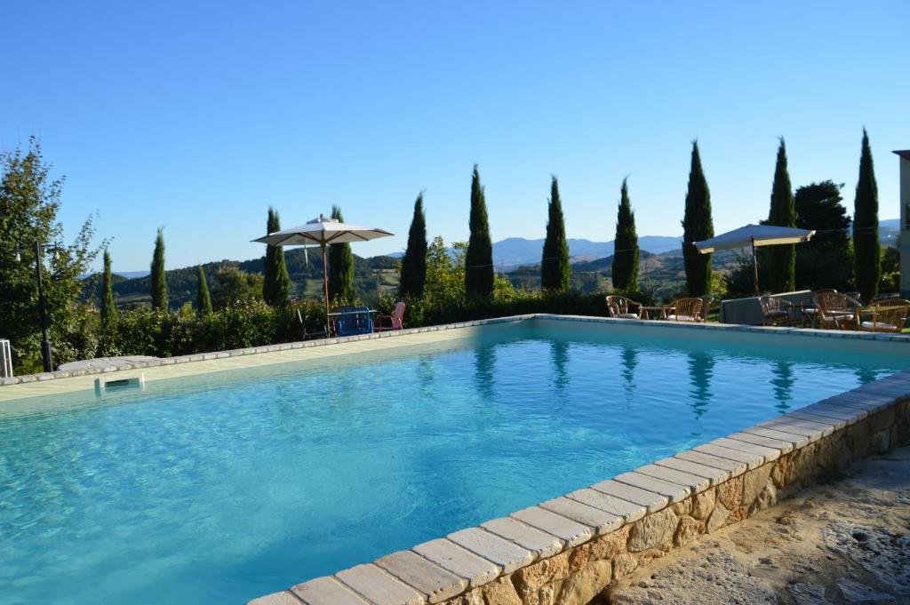 una gran piscina con sillas y sombrillas en Il Borgo Del Lupo, en Sarteano