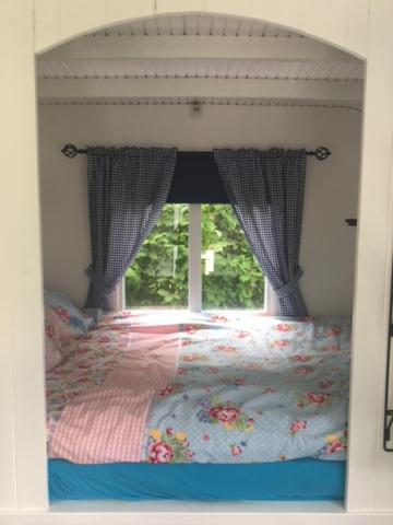 a bedroom with a bed with a window at Shepherds hut (Pipowagen) in Oostvoorne
