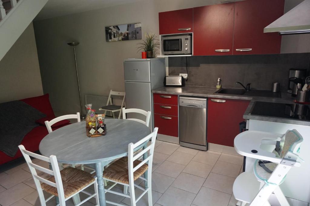 une cuisine avec des placards rouges, une table et des chaises dans l'établissement Gîte agréable et tout équipé La Rochelle, à Dompierre-sur-Mer