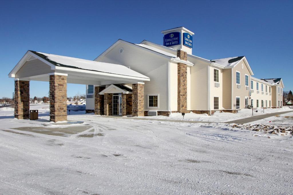 a large white building with a clock tower on top at Cobblestone Inn & Suites - Harvey in Harvey