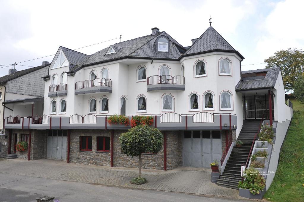 a large white house with a staircase in front of it at Ferienweingut Arnold Fuhrmann & Sohn in Ellenz-Poltersdorf